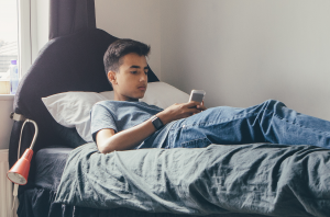 Teen_on_smartphone_on_bed_300_198_int_c1-1x.png